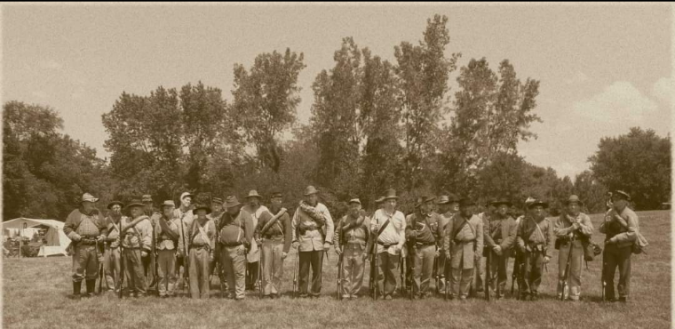 sepia colored image of 44th Tennessee company K, men dressed in confederate uniforms standing in a line in front of a row of trees